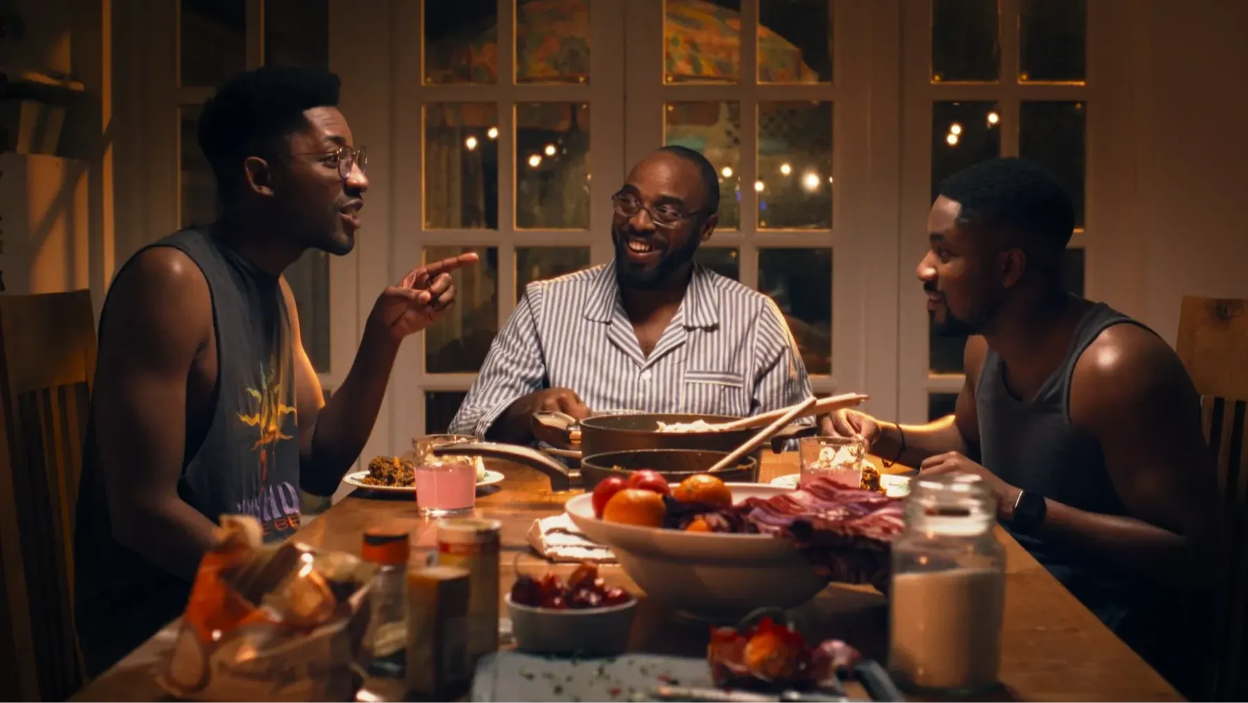 Three Black men engaged in a lively debate around a dinner table.