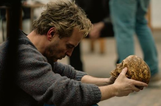 Man holding a skull looking tortured