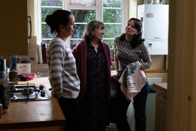 Three women standing in a semi circle in a kitchen