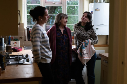 Three women standing in a semi circle in a kitchen