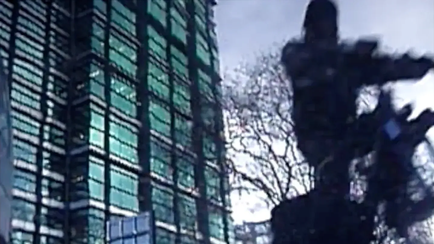 a man on a bike passing a green glass building