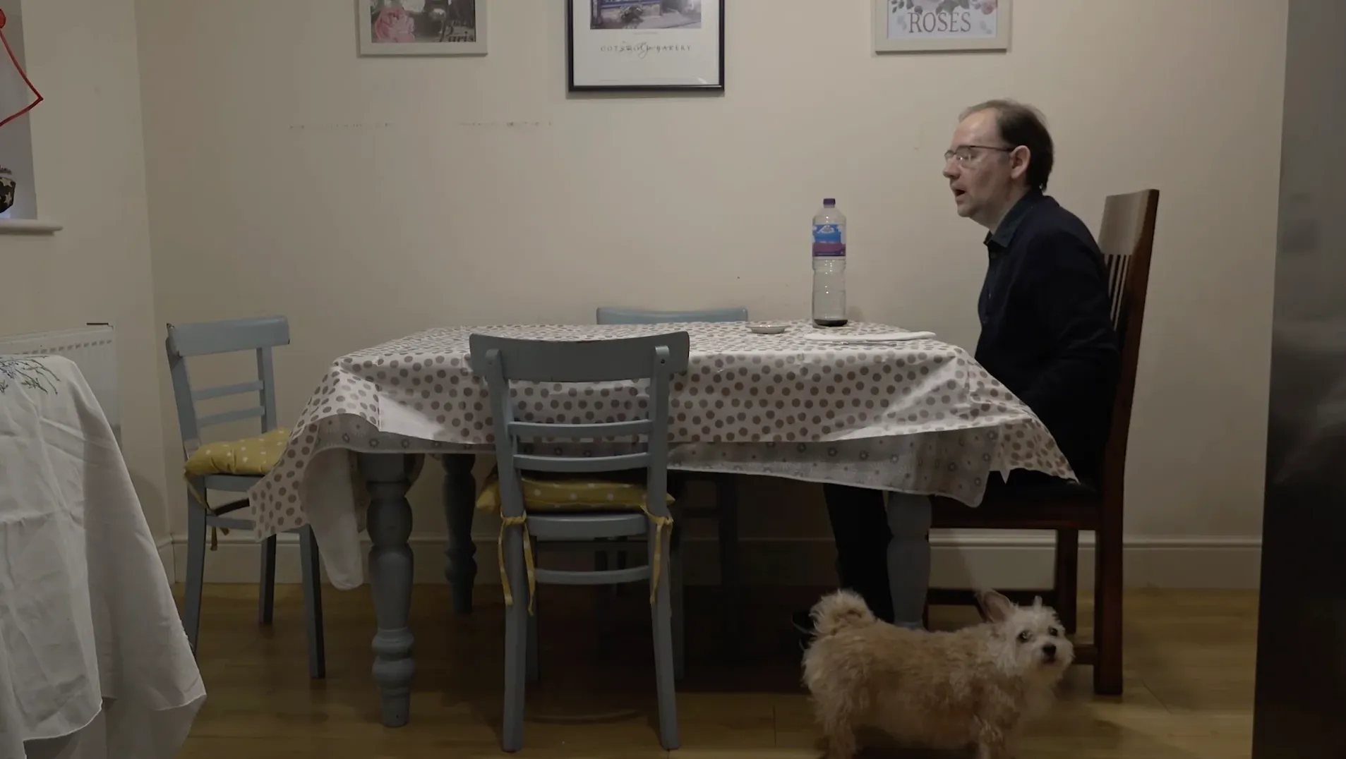 Paolo sitting at dining table with pet dog in the foreground