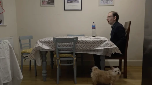Paolo sitting at dining table with pet dog in the foreground