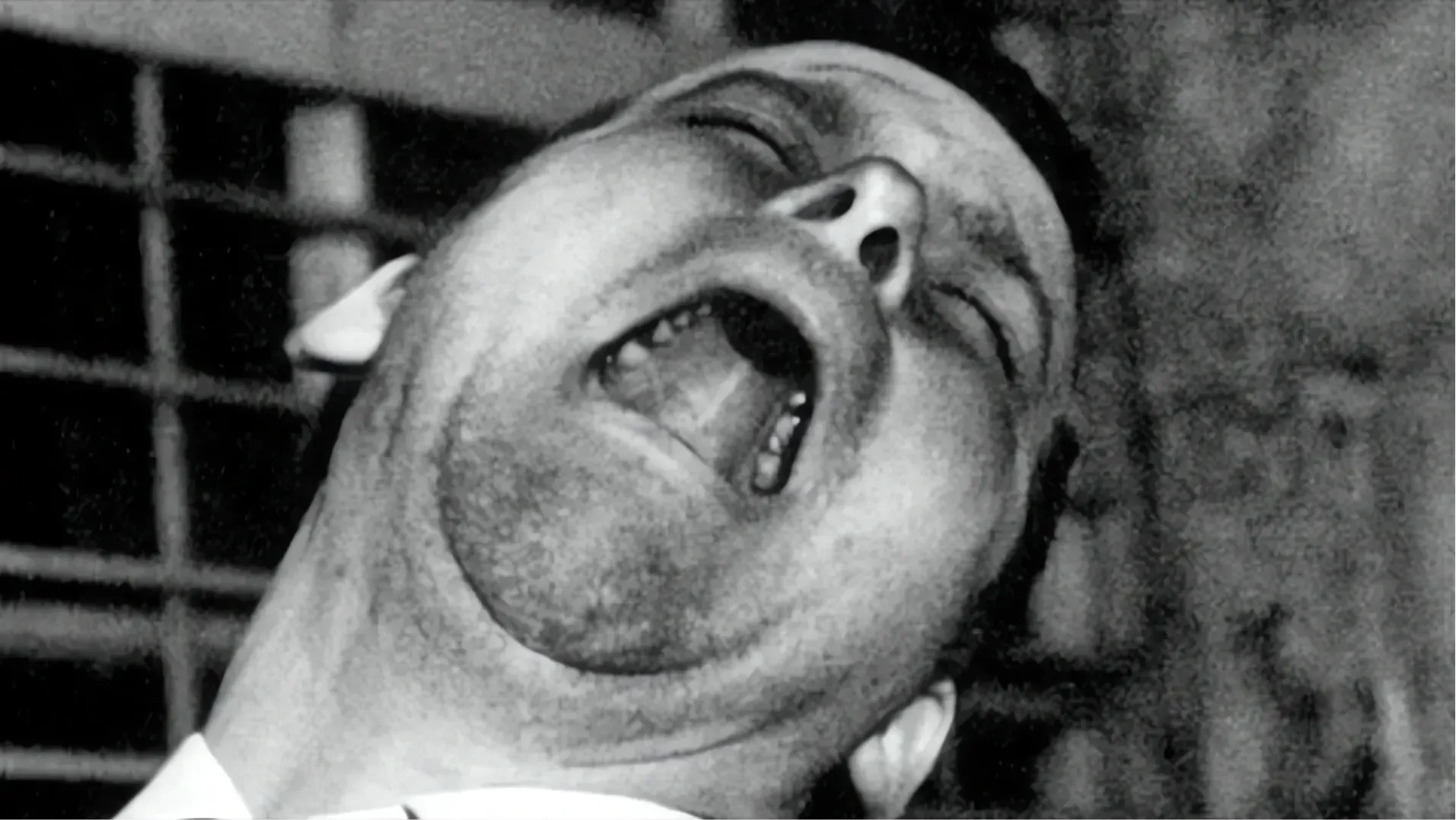 Black and white close-up of a man shouting with his head thrown back