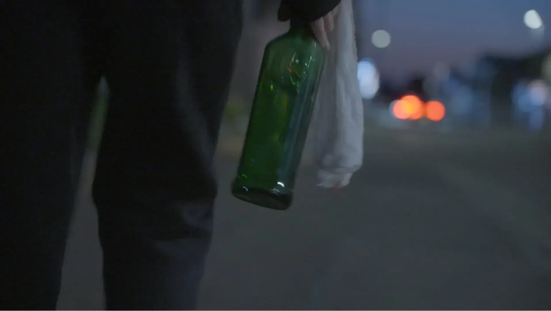man seen from behind carrying a bottle/missile