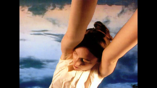A woman reaching up against a cloudy sky