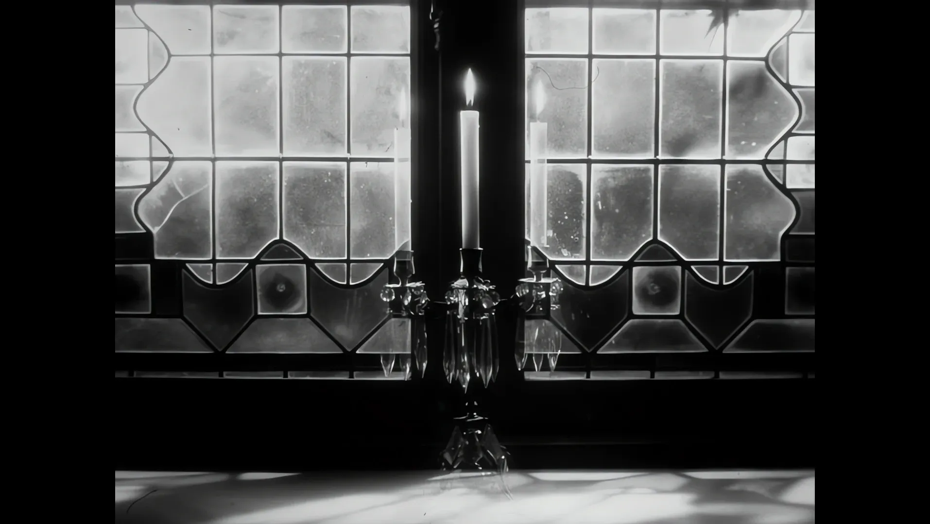 Black and white view through a large window with a candle