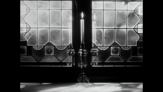 Black and white view through a large window with a candle