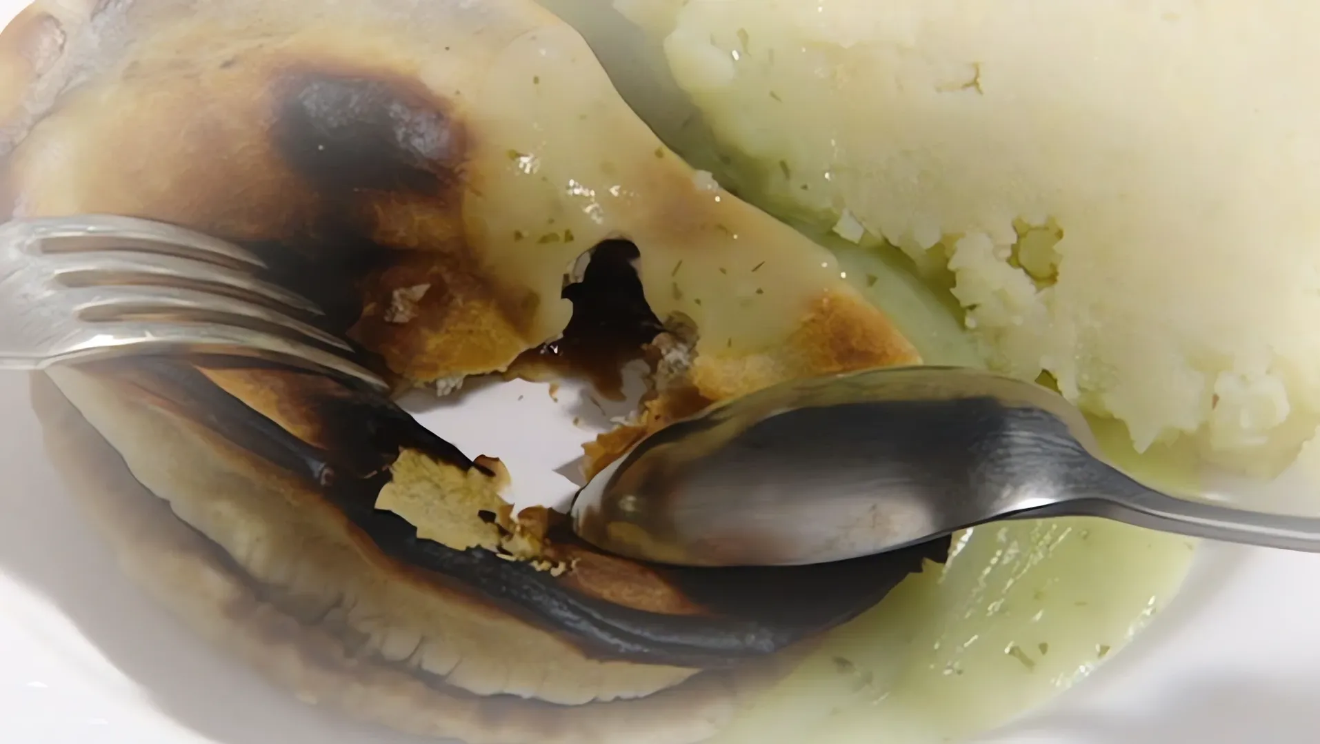 Close-up of mashed food with a fork and spoon on a plate