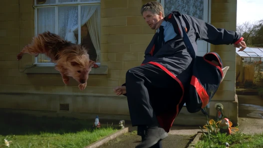 A man in a tracksuit leaps in front of a house while a dog flies through the air