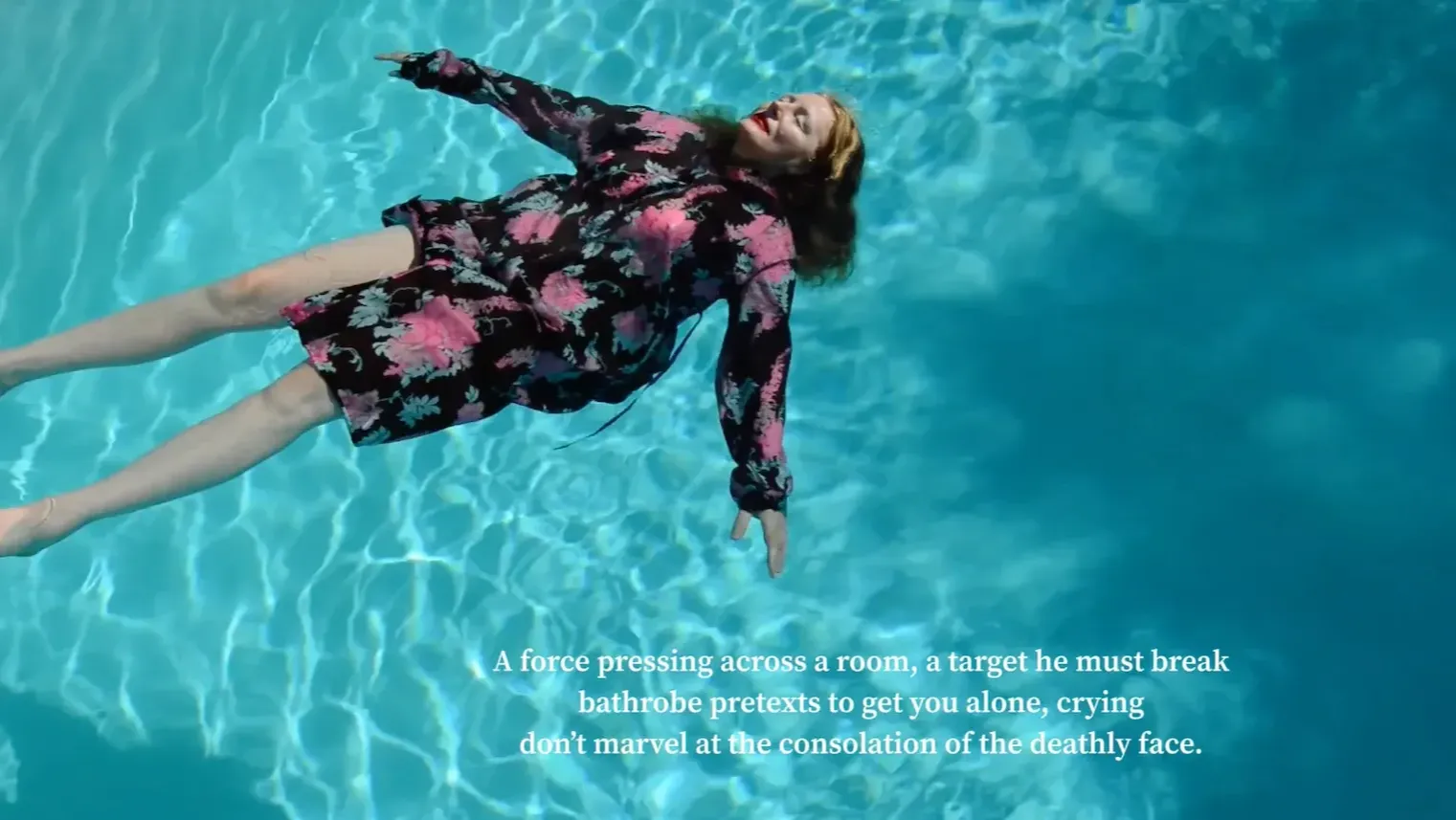 A woman lying in a pool with arms out and poetry beneath her