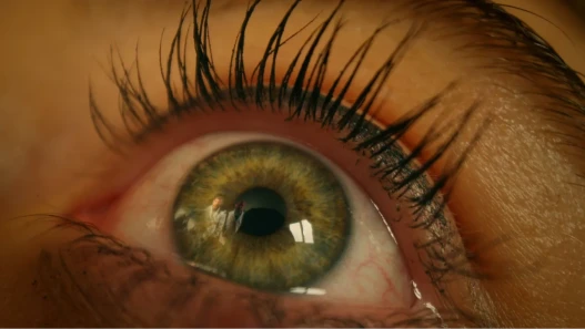 Womans eye open in shock with male figures reflected in it